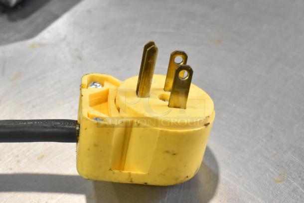 Yellow plug of the Beverage Air SPE60-24M prep table, showing three prongs, on a stainless steel surface.