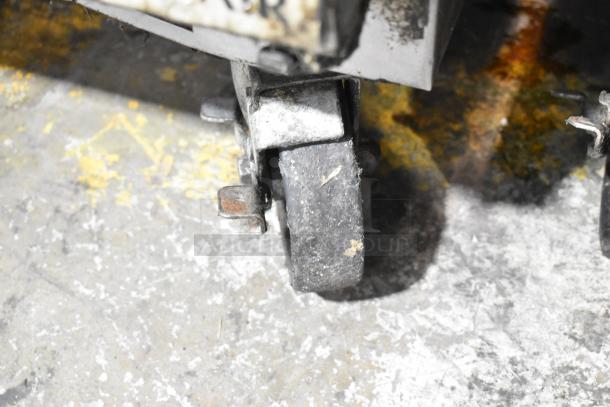 Close-up of a worn caster on a Beverage Air SPE48-18M-HMP prep table. Shows visible rust and wear on the wheel and metal parts.