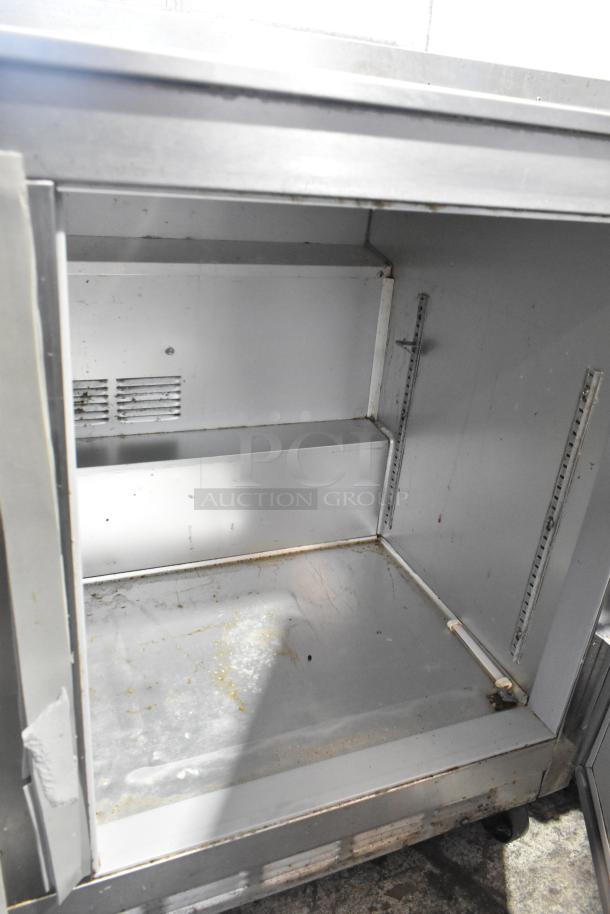 Beverage Air UCR48A stainless steel undercounter cooler, 2 doors, on casters, shows wear, interior shelves visible. 115V, 1 phase.