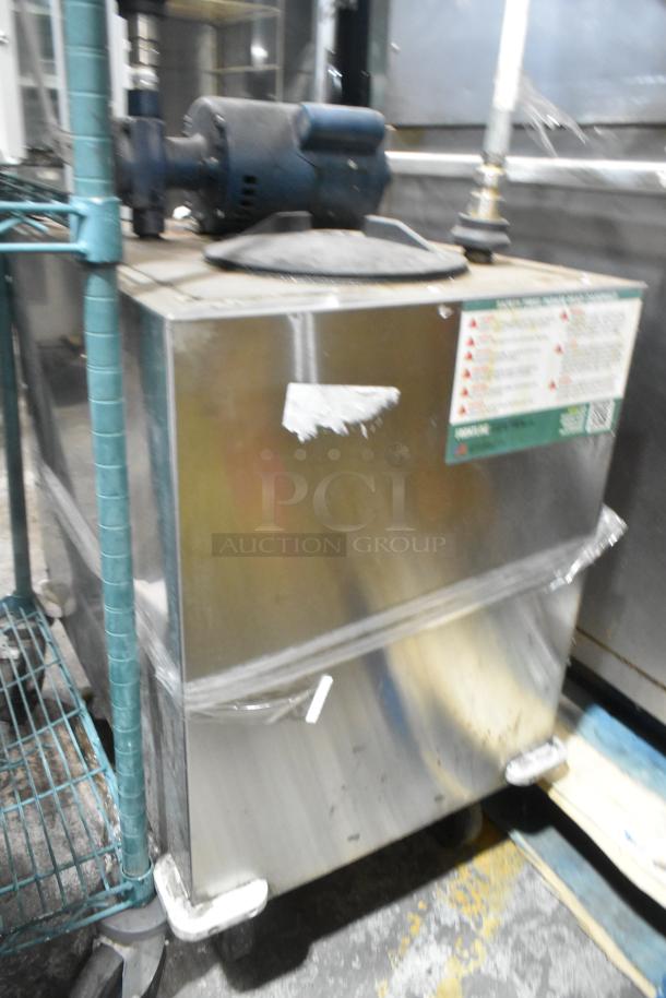 Stainless steel commercial oil filter with lid on commercial casters. Features labels with safety instructions. Used condition.