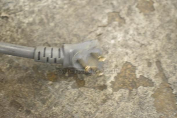Electric plug of an Amana RCS10TS commercial microwave, 120V, shown on a worn surface.
