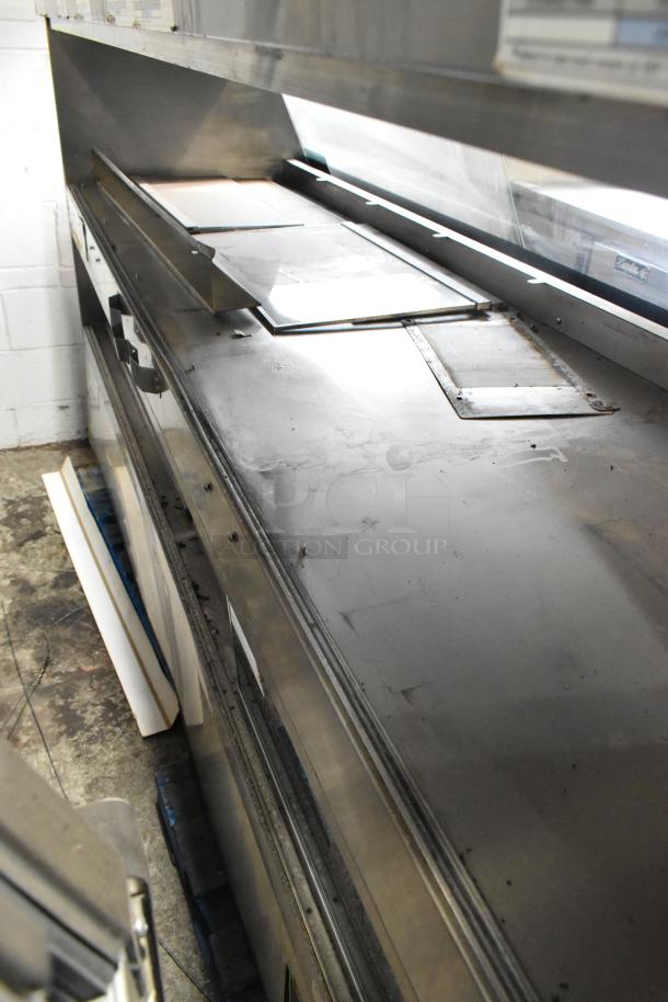 Metal commercial floor-style merchandiser, stainless steel, used condition. Features shelves and display area, ideal for retail.