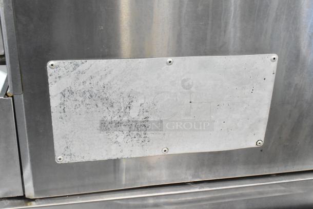 Two L&J NY stainless steel commercial full-size convection ovens with view-through doors, metal racks, thermostatic controls, and commercial casters. Visible metal surface with signs of wear.