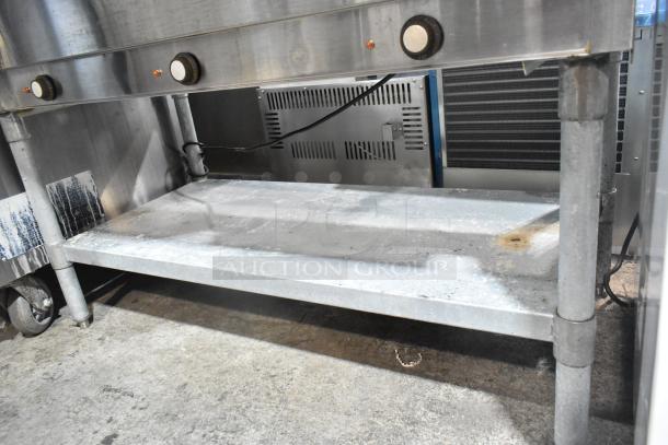 Eagle stainless steel commercial 3 bay steam table with metal under shelf, showing control knobs and visible signs of wear.