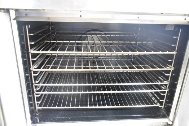 Stainless steel commercial full-size convection oven with thermostatic controls and metal racks, in used condition.