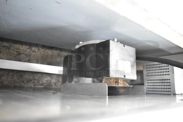 Commercial convection oven interior, showing metal construction and thermostatic controls. Visible metal racks, sturdy design.