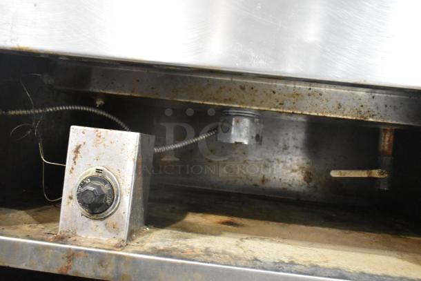 Stainless steel steam table with two wells and cylindrical drop-in bins. Visible wear, control panel, and wiring.