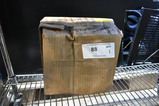Brown cardboard box containing Avantco 177PMX30HIAX axle assembly. Box shows scratch and dent damage. Auction label reads "88, QTY 1, PCIAuctions.com."