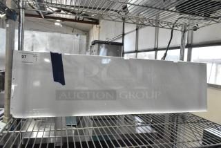 Brand new Avantco white shelf assembly for WVAC-46HC, scratch and dent condition, item number 19386573, auction label on side.