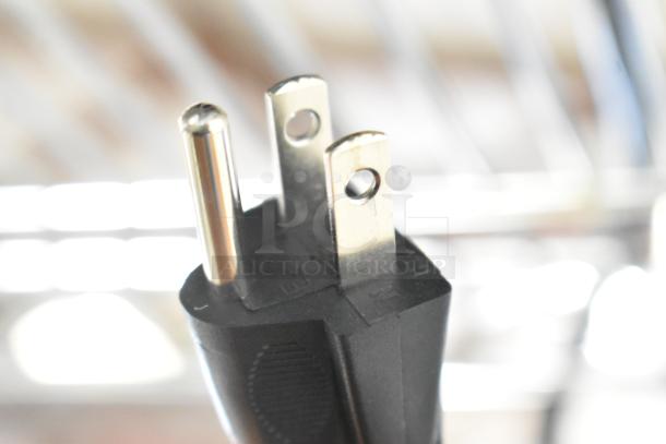 Close-up of a three-prong electrical plug, detailed view of prongs and black casing, part of a 2024 Galaxy blender.