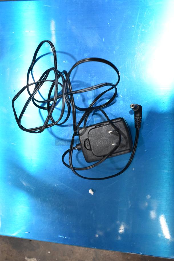 Black power adapter and cable for the AvaTek 334BS330T digital bench scale, on a blue surface.