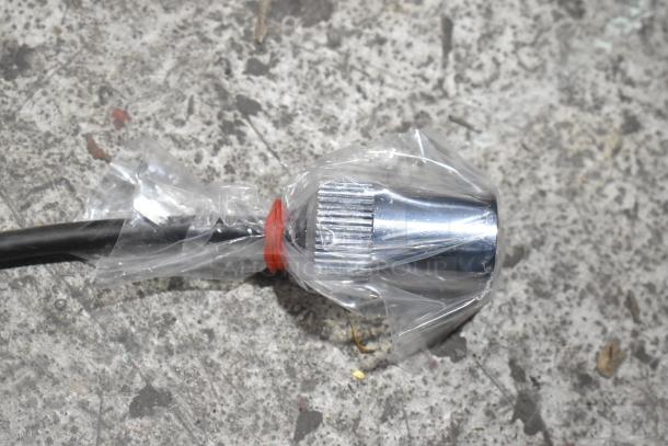 Brand new chrome faucet, partly wrapped in plastic, with minor scratches and dents, on a textured surface.
