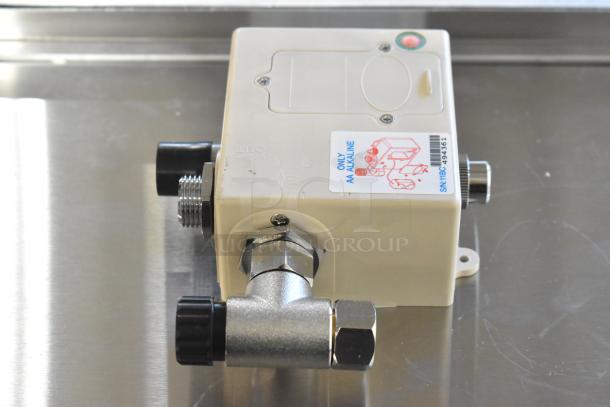 "Brand new scratch and dent box. Cream-colored with visible fittings and connectors. Label indicates AA alkaline compatibility."