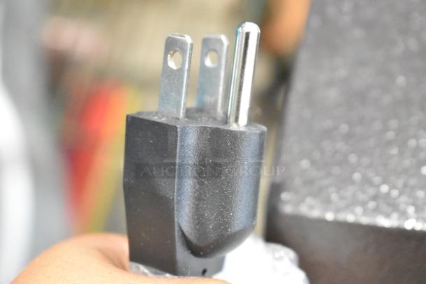 Close-up of a three-prong electrical plug from a 2024 Avantco 177HDC26 heated display case, 120 volts, missing glass.