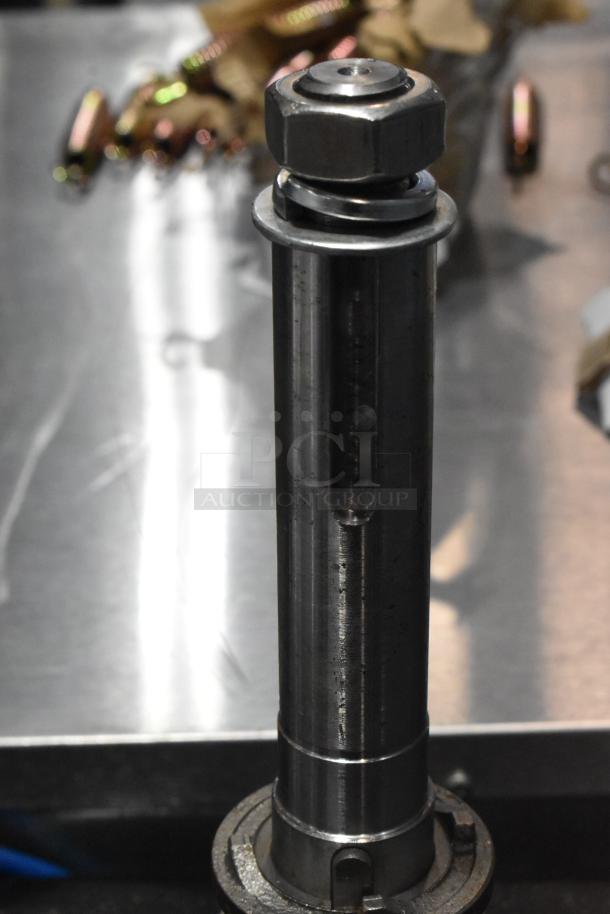 Brand new metal gear with scratches and dents, cylindrical shape, steel material, shiny finish, mounted on metal surface.