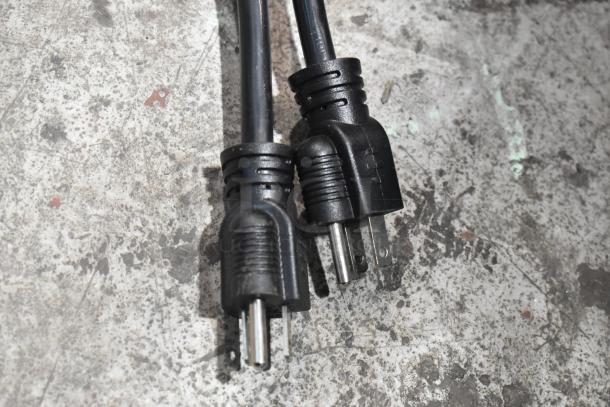 Black power plugs on a scratched, textured metal surface.