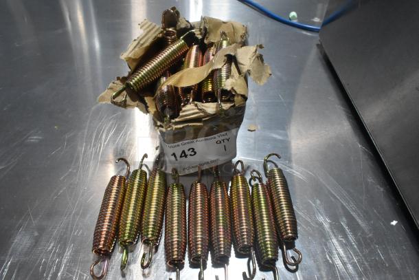 Box of new metal door springs, slight packaging damage. Springs are coiled, various colors. Label reads "143, QTY 1".