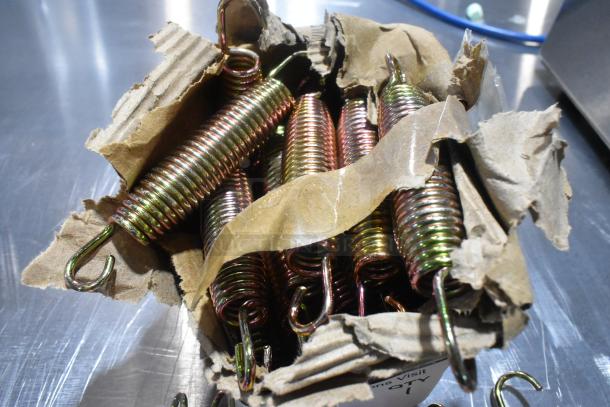 Box of new metal door springs, scratch and dent condition. Springs in cardboard packaging show slight cosmetic imperfections.