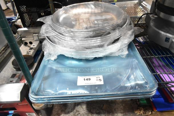 Stack of new aluminum trays and sheet pans, wrapped in plastic, labeled as scratch and dent items, on a metal rack.