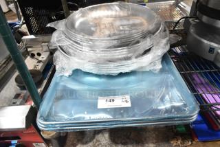 Stack of new aluminum trays and sheet pans, wrapped in plastic, labeled as scratch and dent items, on a metal rack.