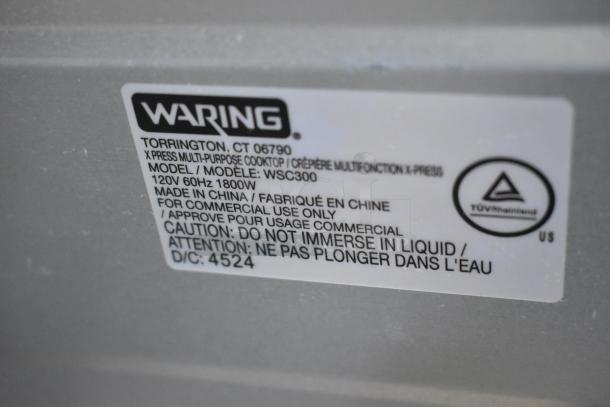 Label on Waring XPress WSC300 electric cooktop showing model, voltage, and caution against liquid immersion.