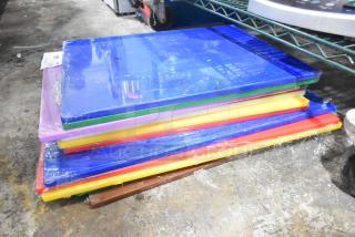 Stack of 12 colorful, brand-new scratch and dent cutting boards, sizes 20"x15"x1/2" and 24"x18"x1/2", wrapped in plastic.