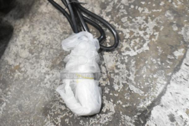 Plastic-wrapped electrical cords on concrete surface, part of a Carnival King beverage dispenser package.