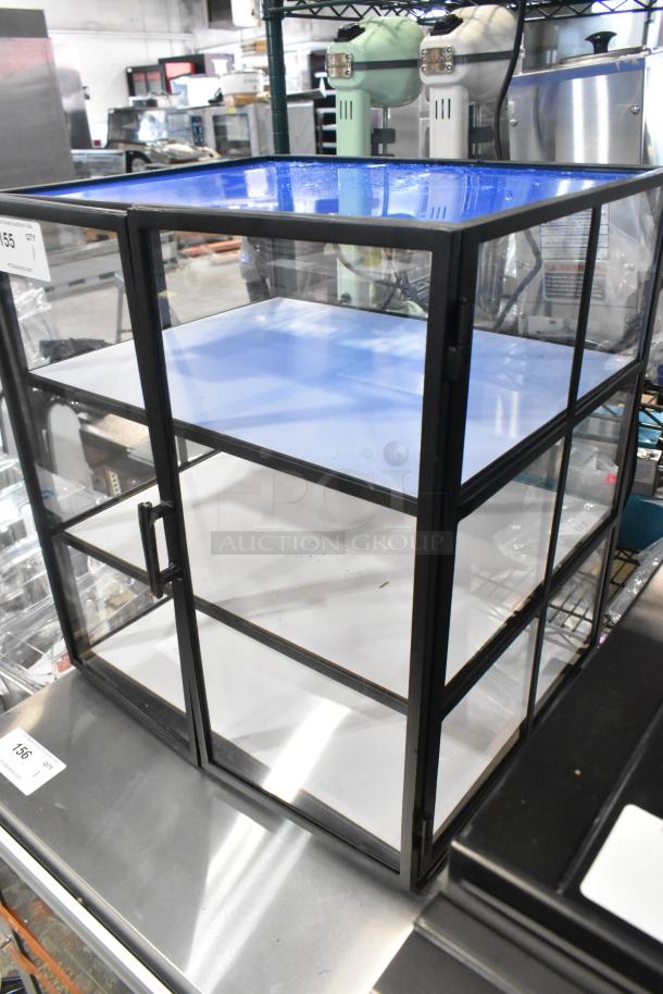 Brand new countertop dry display case merchandiser, black frame, three shelves, minor scratches, ideal for showcasing items.