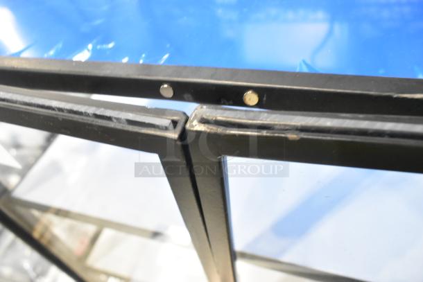 Brand new countertop dry display case merchandiser with visible scratches and dents, black frame, and clear panels.