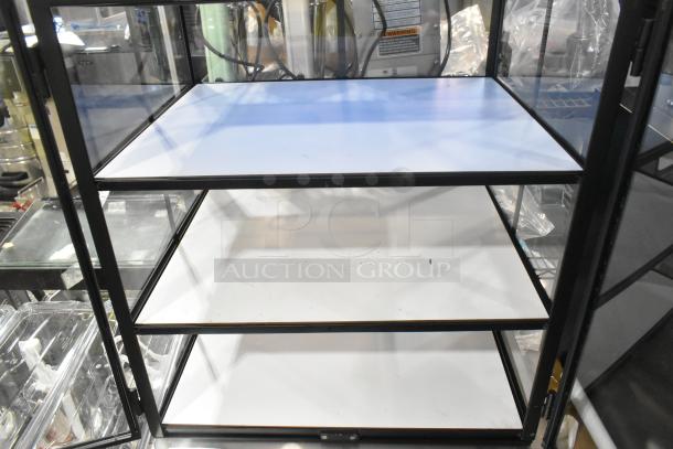Brand new countertop dry display case merchandiser, glass panels, black frame, three white shelves, minor scratches.