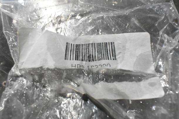 Transparent plastic bag with sticker label, barcode, and code "HP1183200" visible. Bag slightly crumpled, reflects light.
