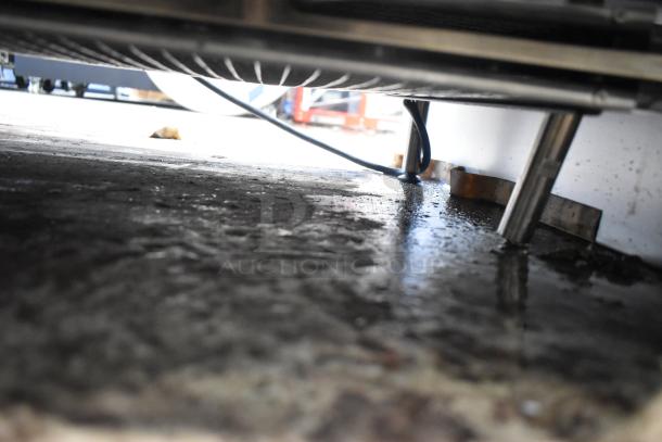 A close-up view underneath a Narvon slushie machine showing metal legs and wiring, with visible floor scratches and dents.