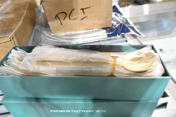 Two brand new boxes of Premium Flatware Sets, slightly scratch and dent, in original packaging, wrapped in plastic.