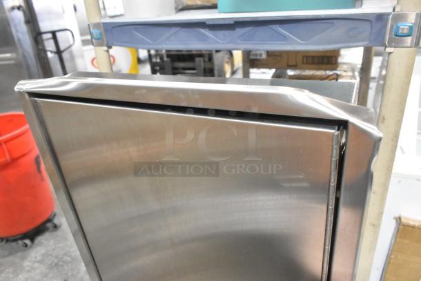 Stainless steel wall mount trash and towel dispenser, brand new with visible dents and scratches.