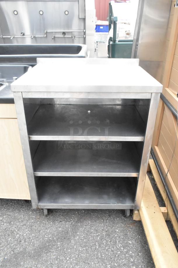 Stainless steel counter with three under shelves, on wheels. Durable, used condition, ideal for kitchen or industrial use.