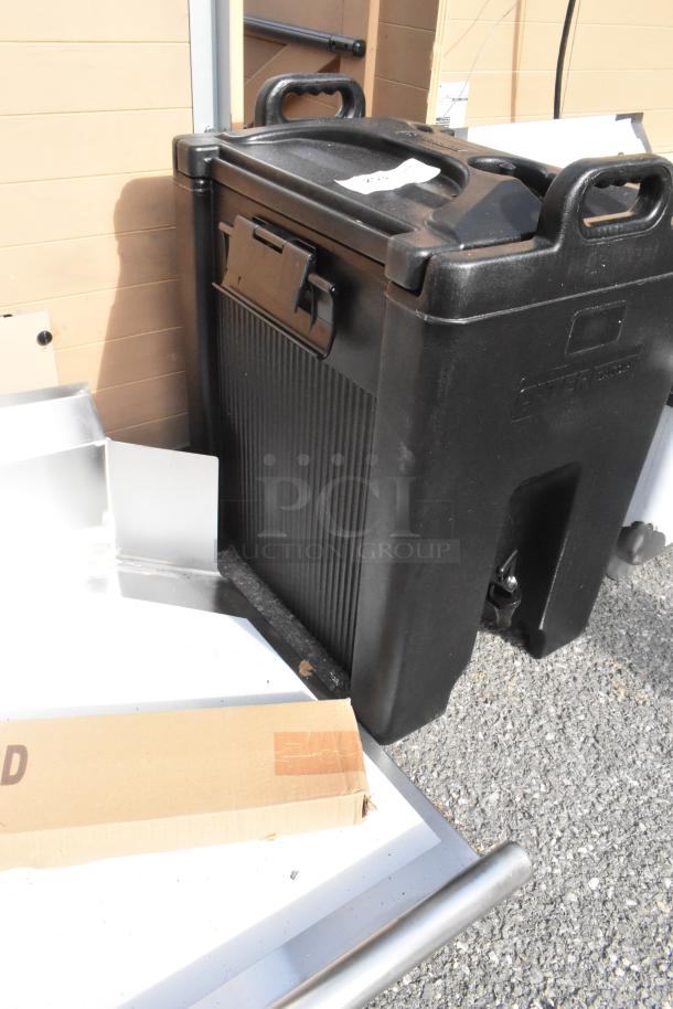 Brand new Cambro 10-gallon black insulated beverage dispenser with visible scratches and dents. Durable build.