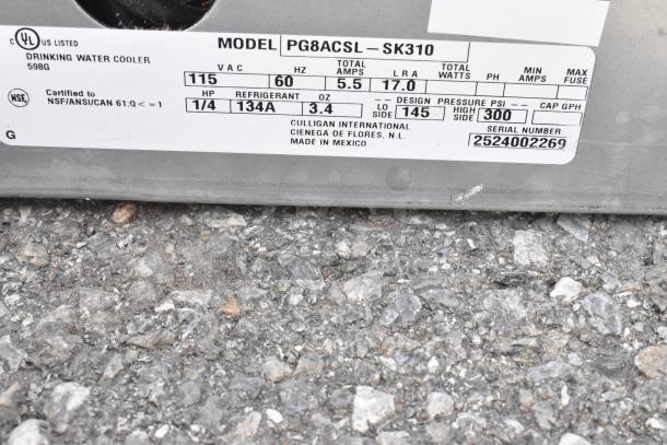 Close-up of Oasis PG8ACSL-SK310 drinking fountain label, showing 115 volts, 1 phase, and certification details.