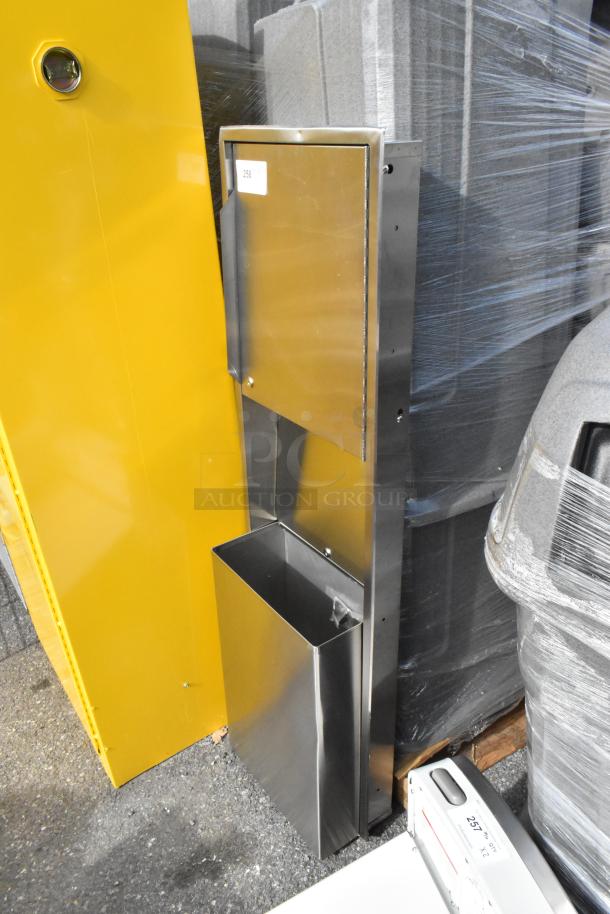 Stainless steel wall mount trash and towel dispenser, brand new with scratches and dents, durable design, ID tag visible.
