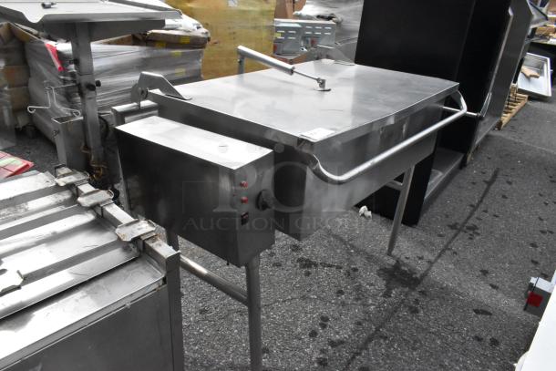 Stainless steel commercial floor-style braising pan with lid and control panel, showing sturdy legs and slight surface wear.