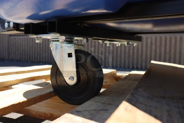 Brand new Rubbermaid® 2089826 BRUTE blue recycling tilt truck on wooden pallet, showing caster detail; one caster missing.