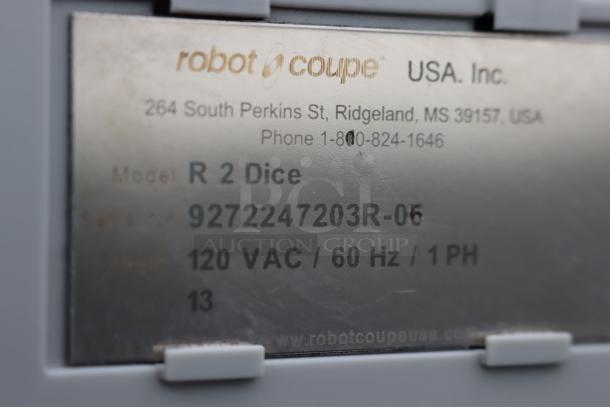 Metal tag on Robot Coupe R2 Dice food processor showing model, serial number, and electrical specs.