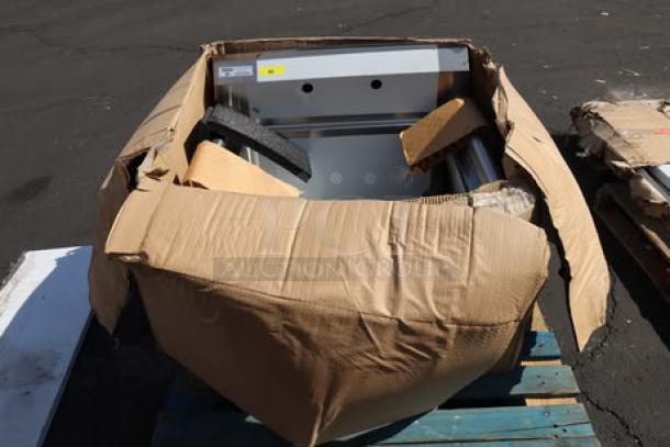 Steelton stainless steel commercial sink, model 522CS12424, with dents, shown partially unpacked in damaged packaging.