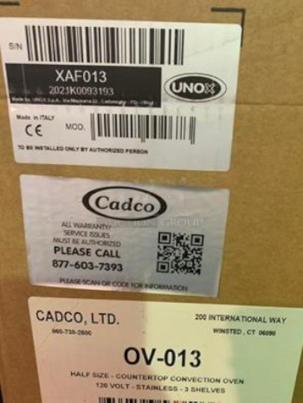 Brand new Cadco OV-013 half-size convection oven in unopened box. Stainless steel, 120V, with visible model and contact labels.