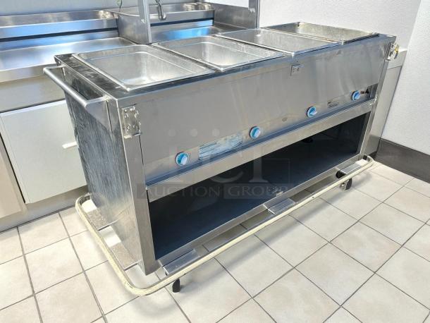 Duke E304 hot food table with four wells and cutting board, tested, 58 3/8" width, stainless steel, 240v, excellent condition.