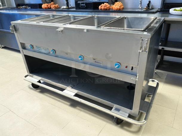 Duke E304 hot food table with four wells, cutting board, and wheels; tested, working, 240v/1ph; stainless steel; excellent condition.