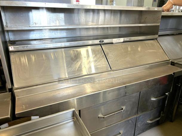 Stainless steel commercial prep station with sliding doors, shelves, and drawers. Light wear visible. Label shows "195."