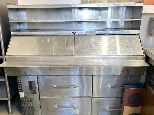 Vintage stainless steel commercial refrigerator with two drawers and top shelf, showing minor wear. Ideal for restaurant use.