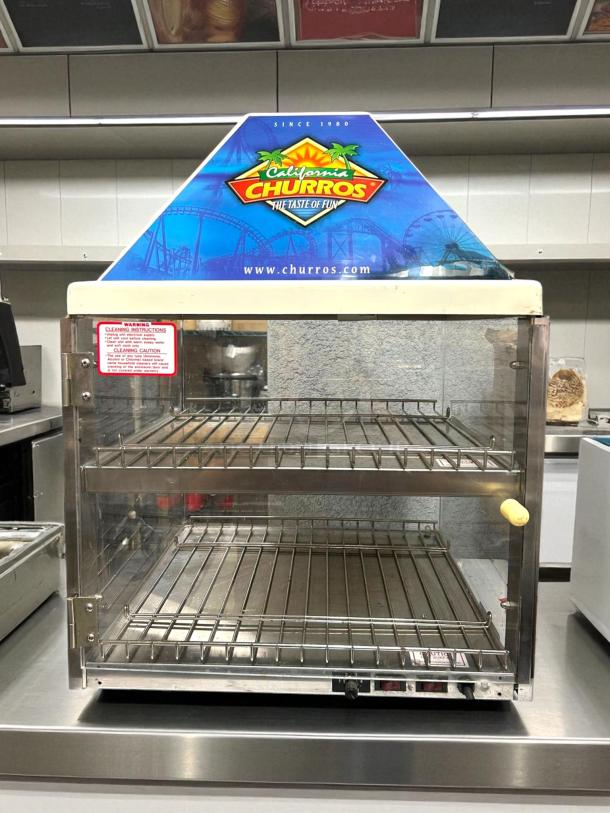 Wisco 680-1 Food Warming Merchandiser, black cabinet, single door, 2 shelves, excellent condition, "California Churros" signage.