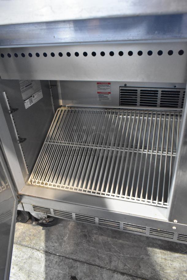 Beverage Air SPE60-24M stainless steel prep table, interior view, shows wire racks and labels. Commercial casters visible.