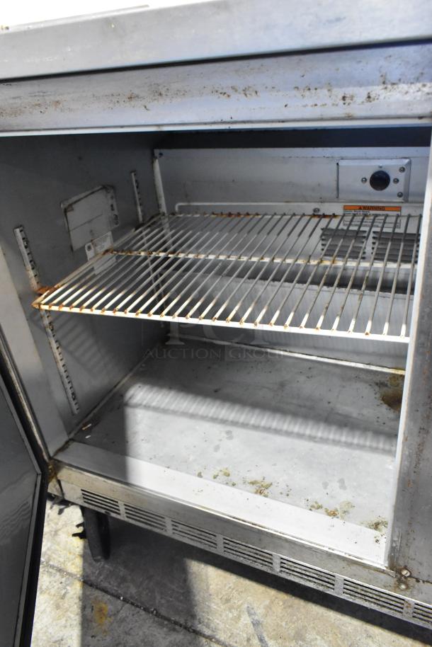 Beverage Air stainless steel 2-door undercounter cooler on casters, showing interior shelves, 115 volts, 1 phase. Some wear visible.